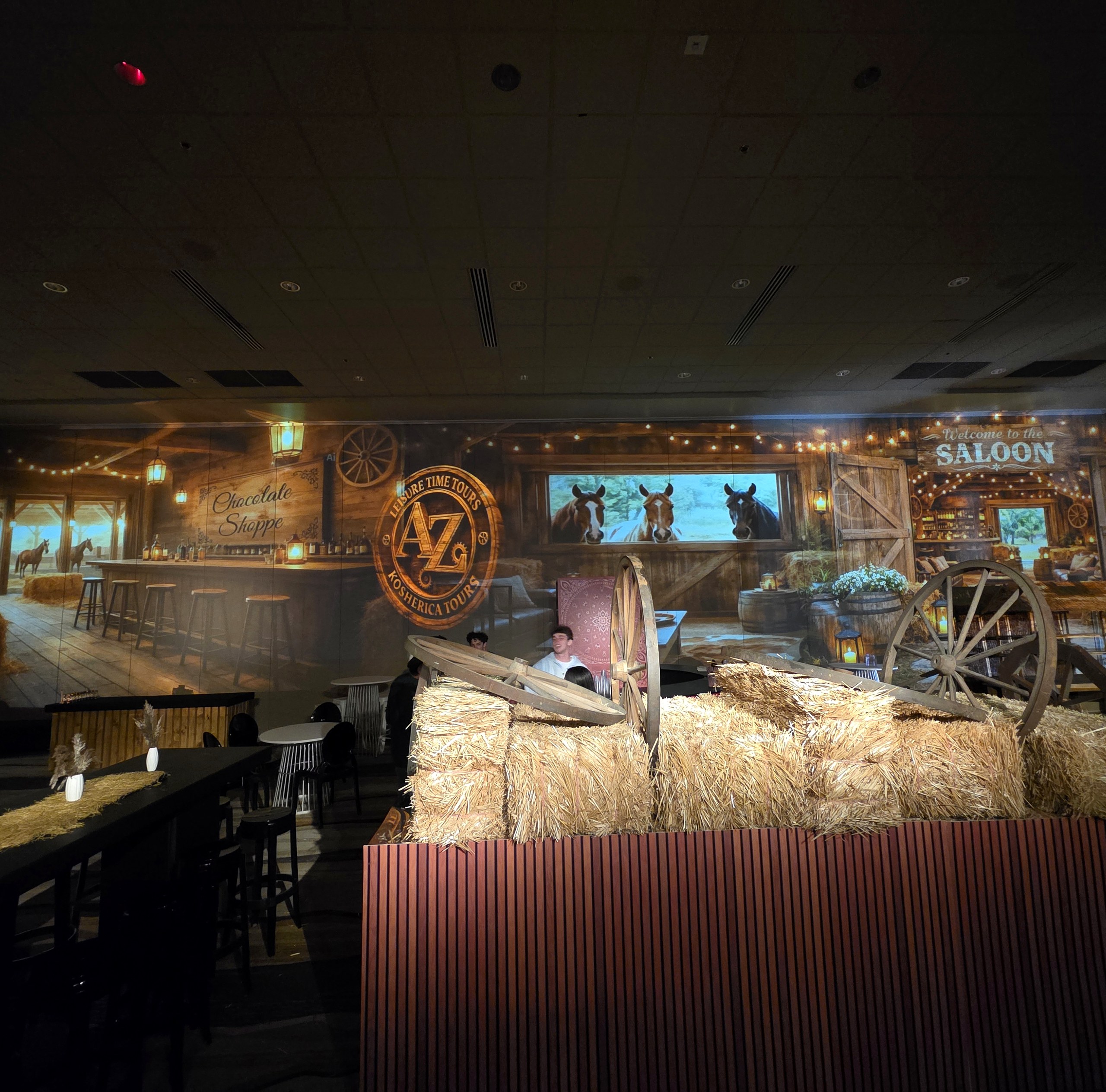 A whole room turned into a barn: horses at the window, string lights, a saloon at the far end