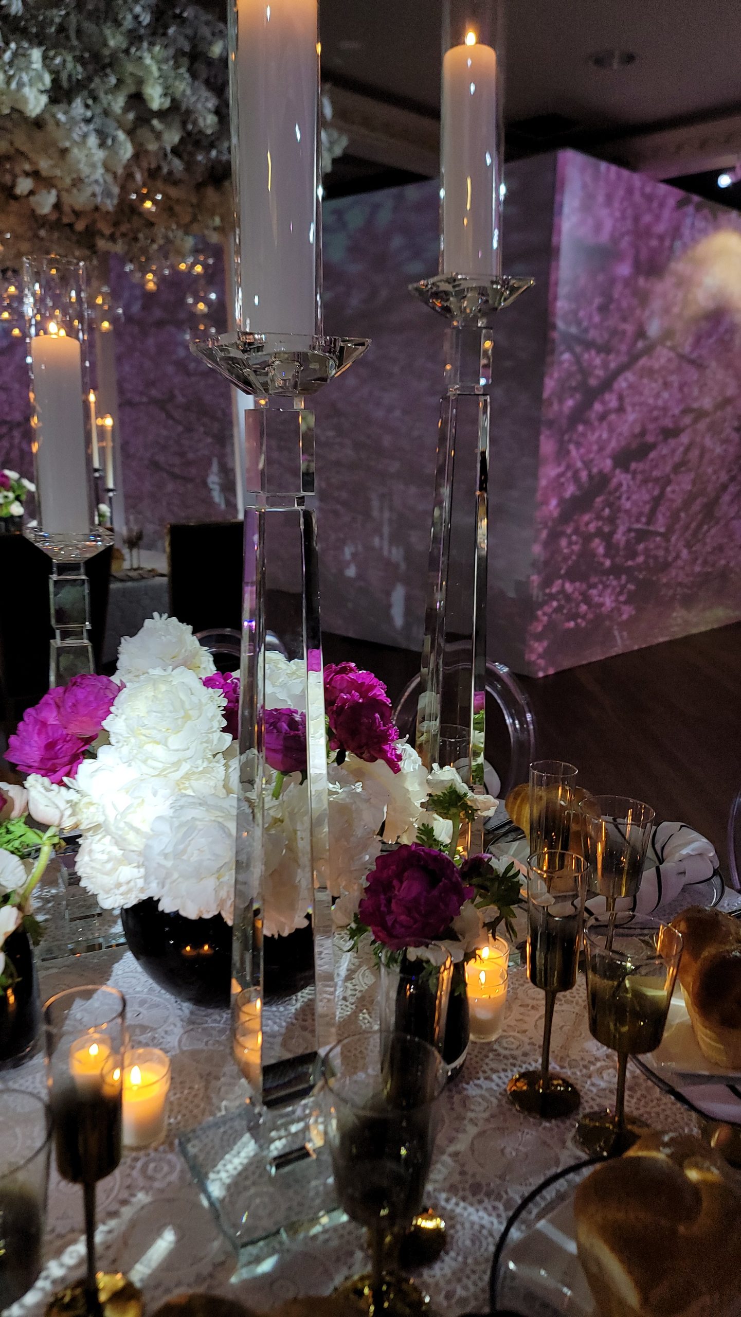 Cherry trees projected on the wall behind the tapers and white florals