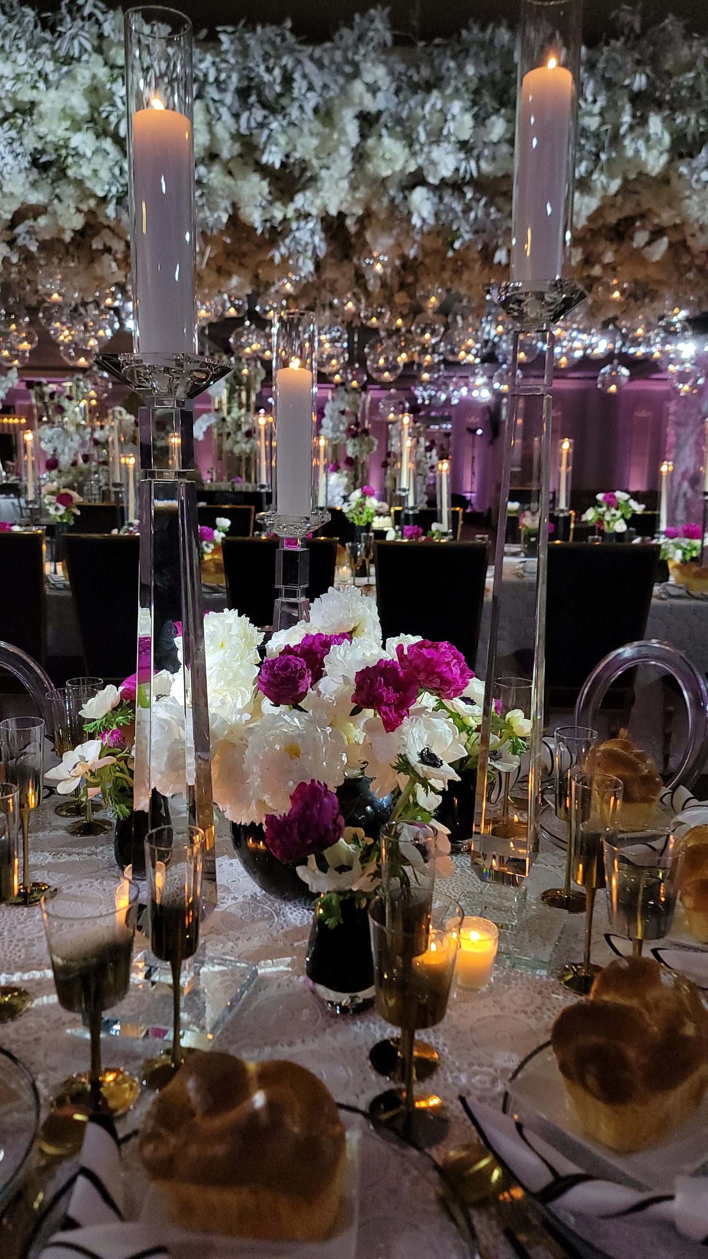 The white blossom canopy filling the ceiling, tapers rising to meet it, the room lit lilac