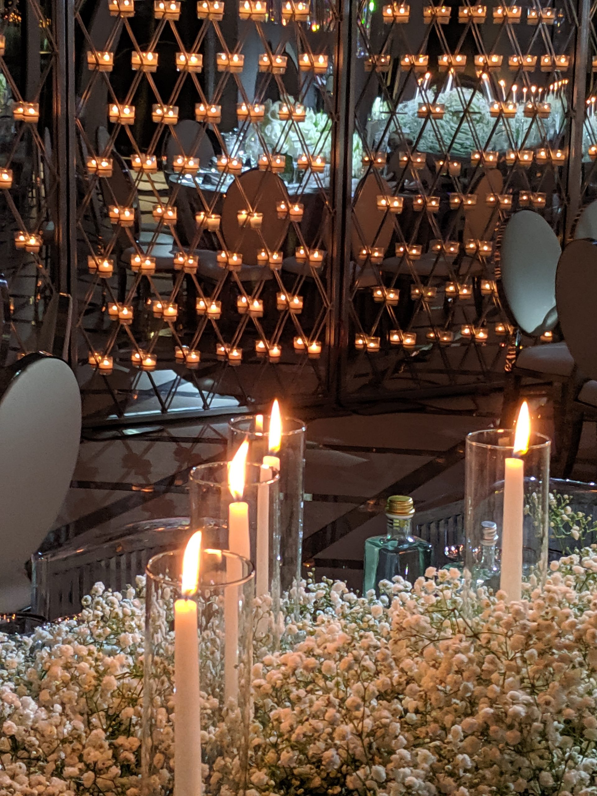 The candle wall close: hundreds of small flames in their lattice, a white chair in front