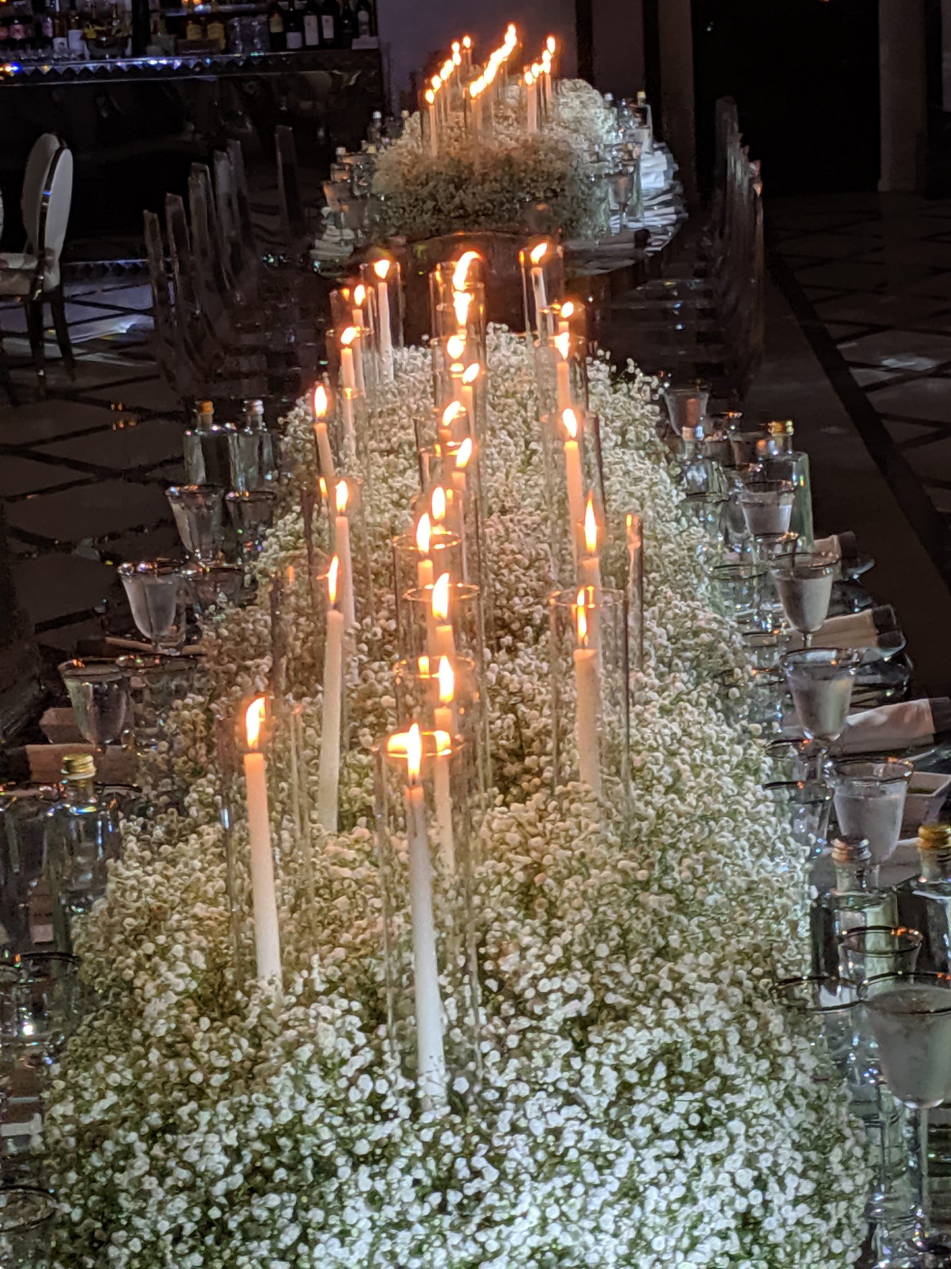 Tapers rising out of baby's breath down the long mirrored table