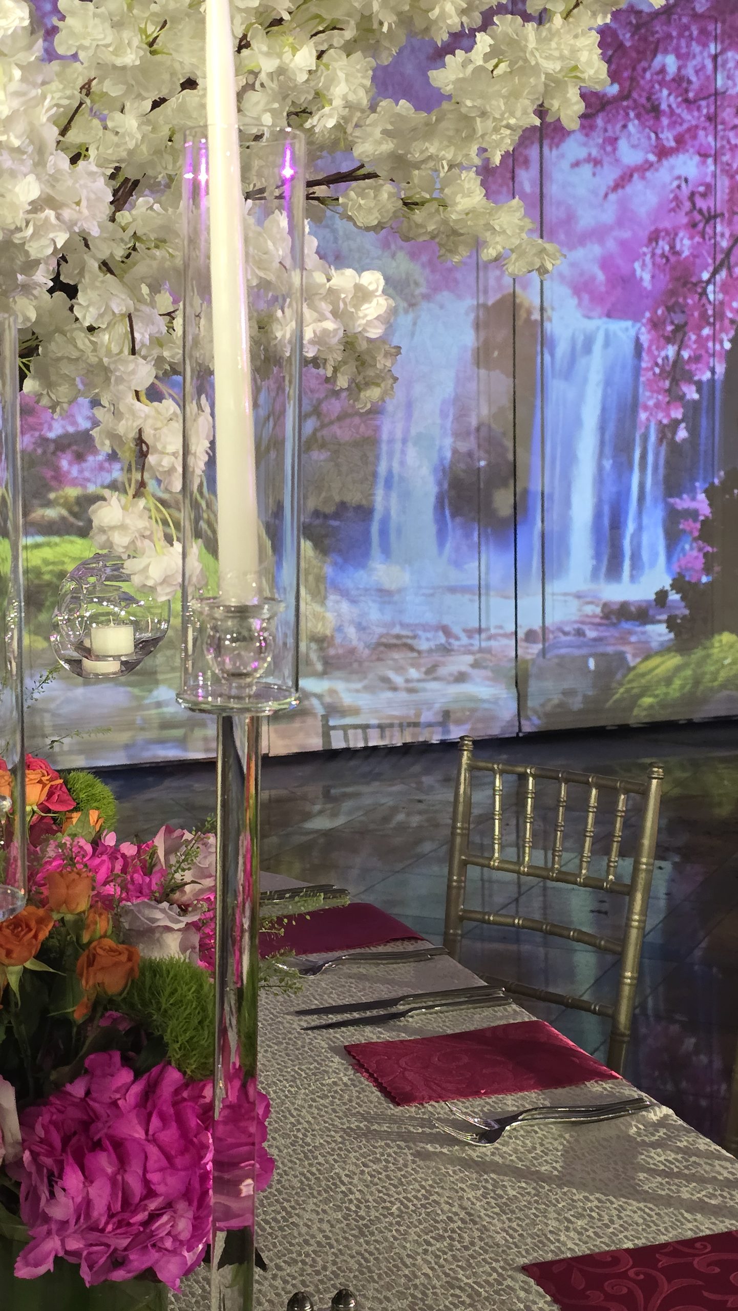 The projected waterfall on the wall behind a candle and a white blossom tree