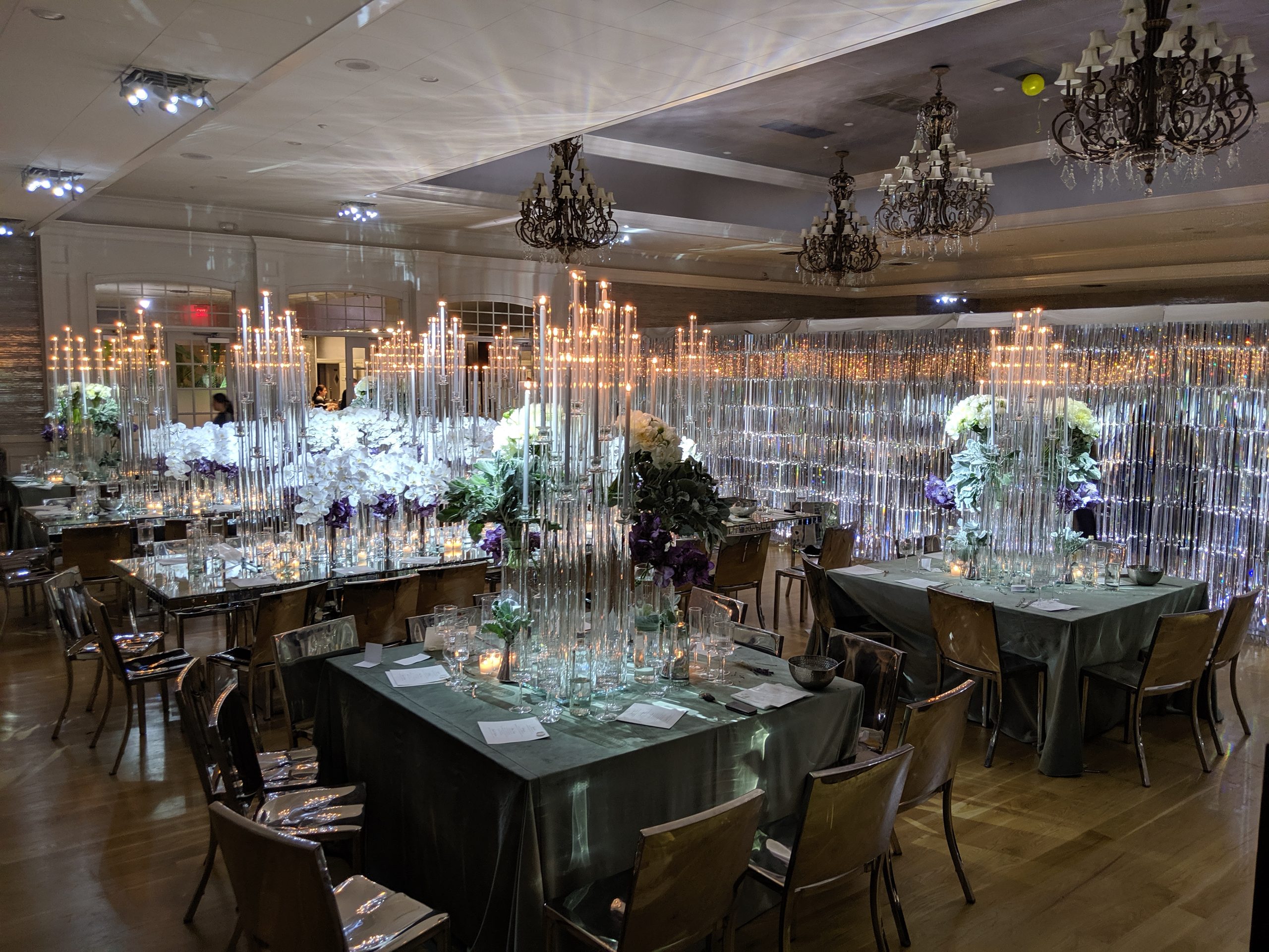The room from the corner: green velvet tables, the tapers, the crystal curtain lit