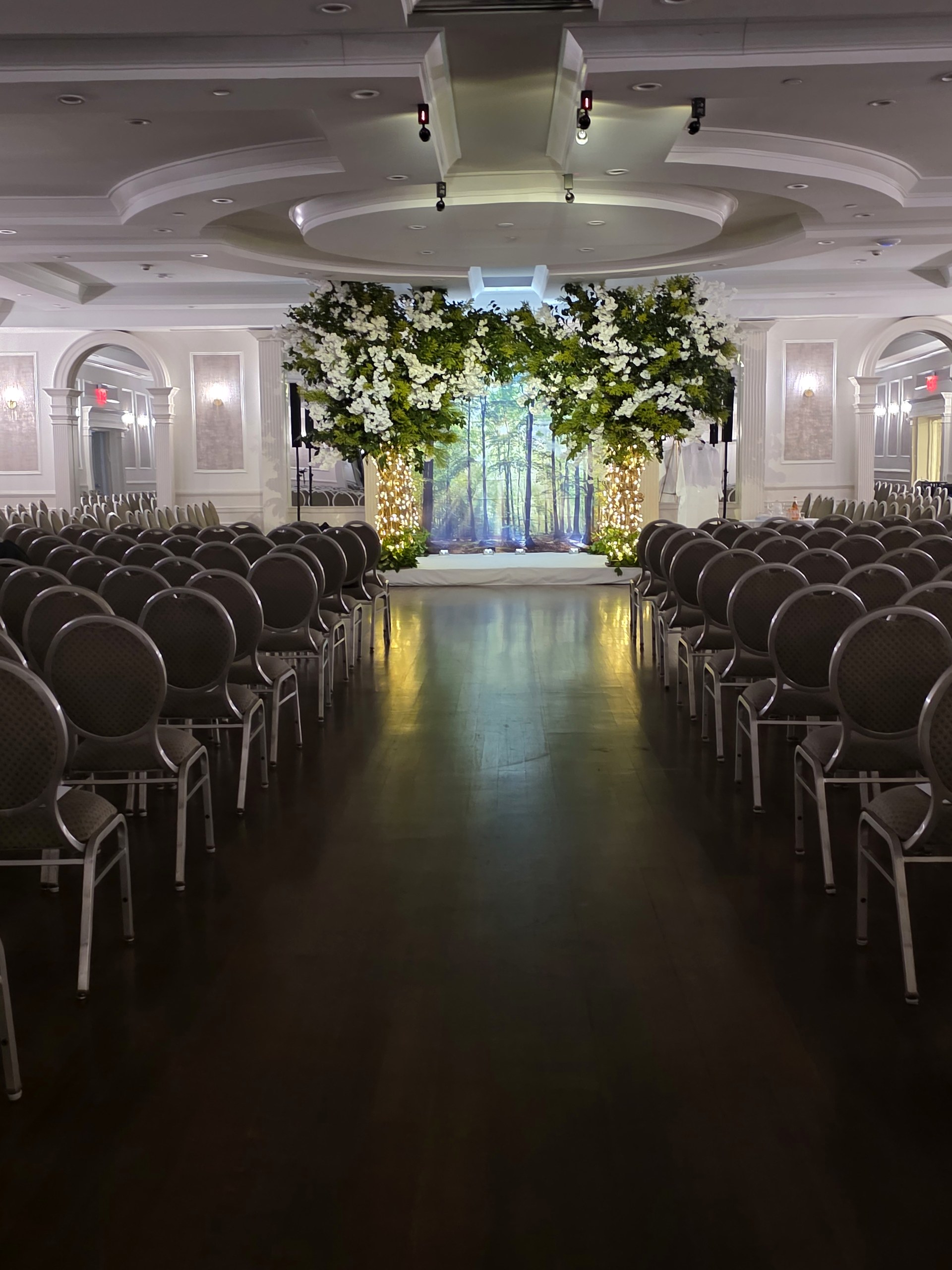 Down the aisle to a chuppah lit inside a projected forest