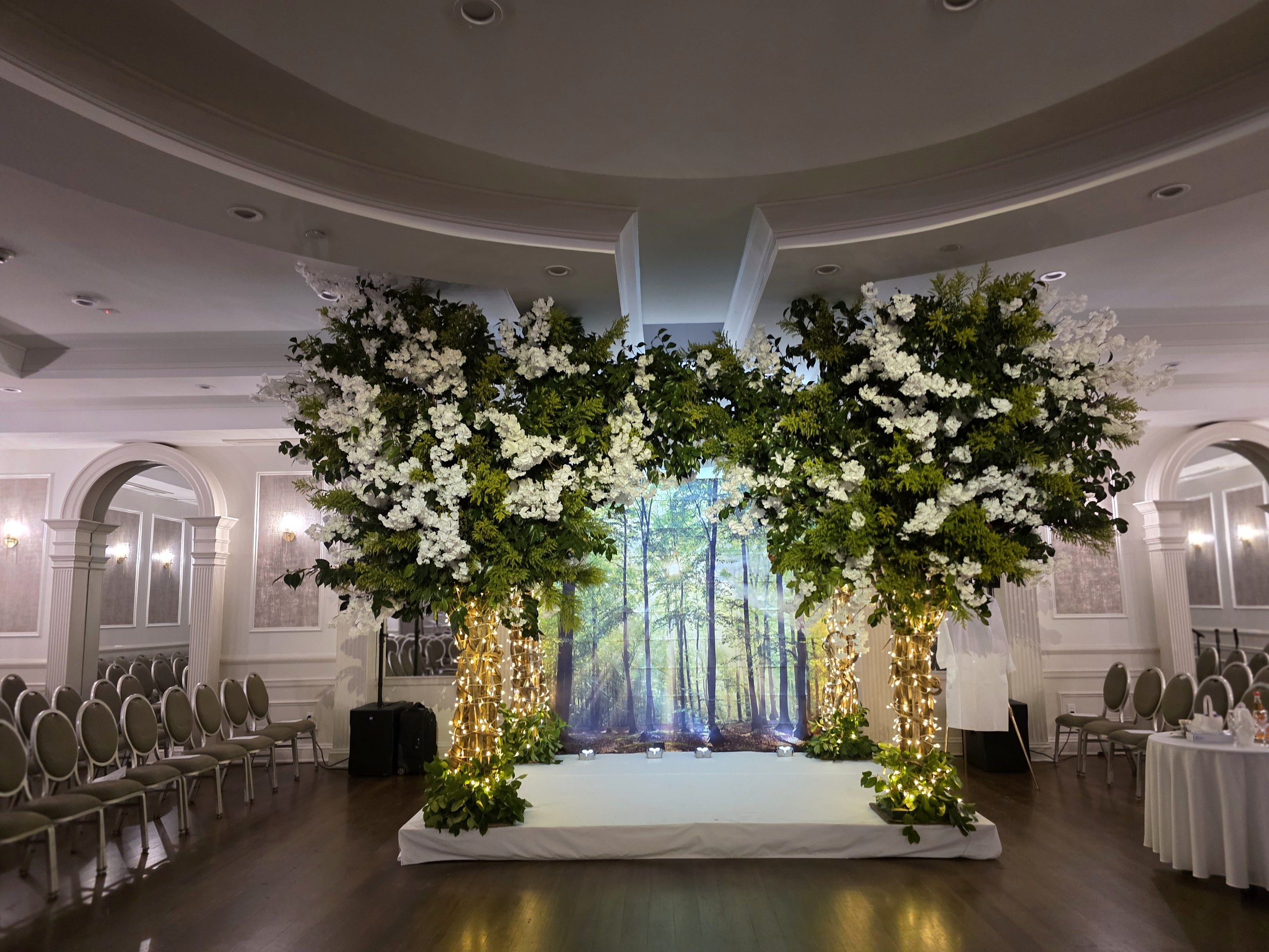 The chuppah: two flowering trees, a sunlit forest projected between them