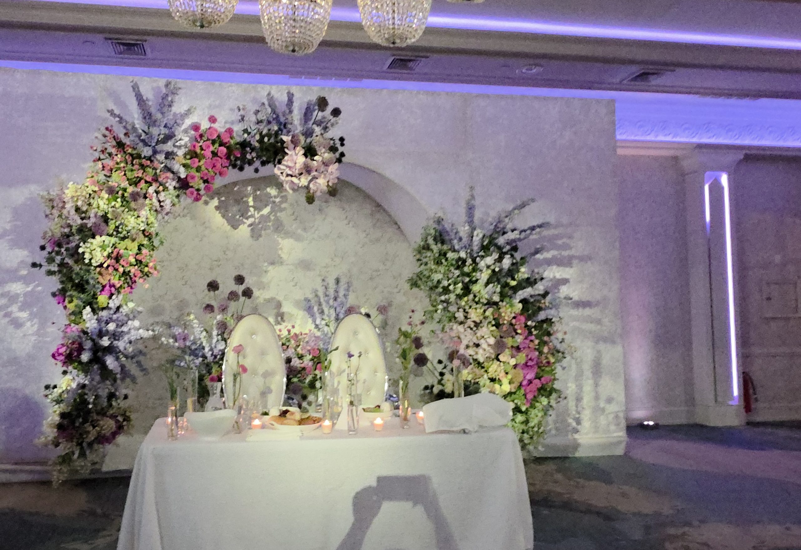 The floral backdrop and white sofa for the couple, lavender and blush