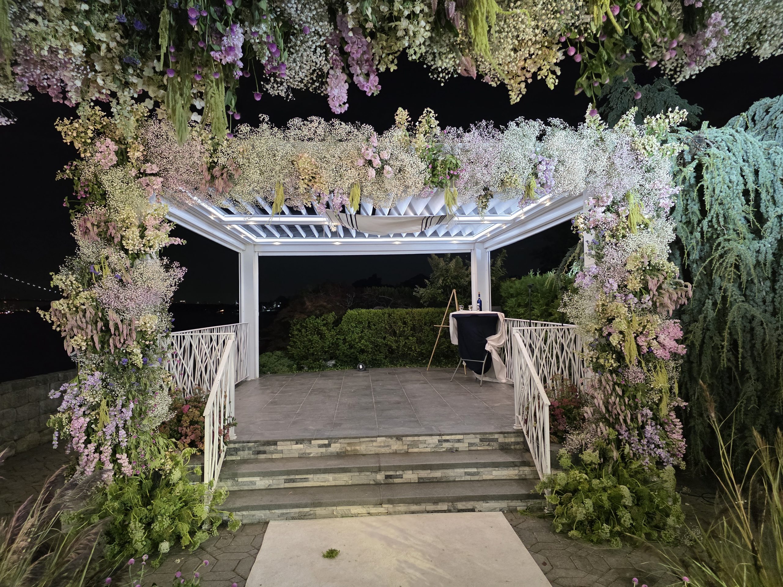 The garden pergola outside, dressed in florals and lit for the chuppah