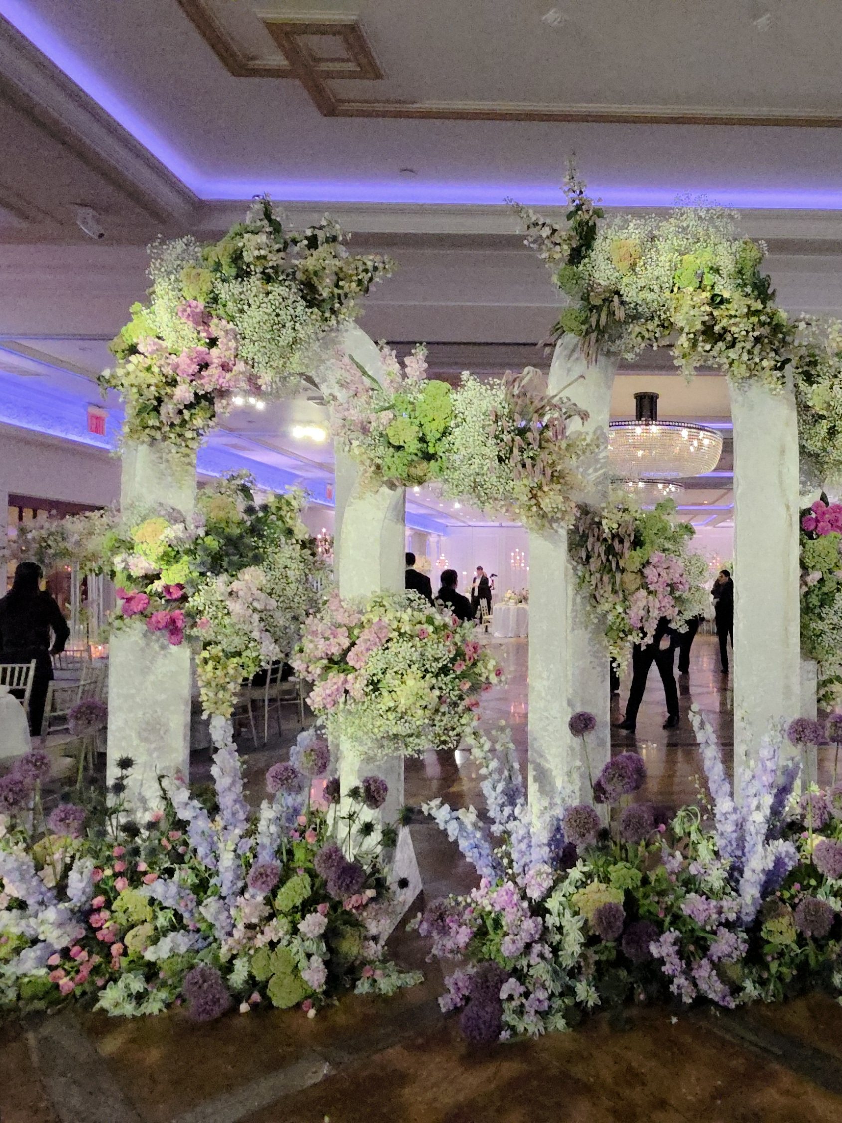 The ballroom: floral arches along the walls, the tables set, the room washed lilac