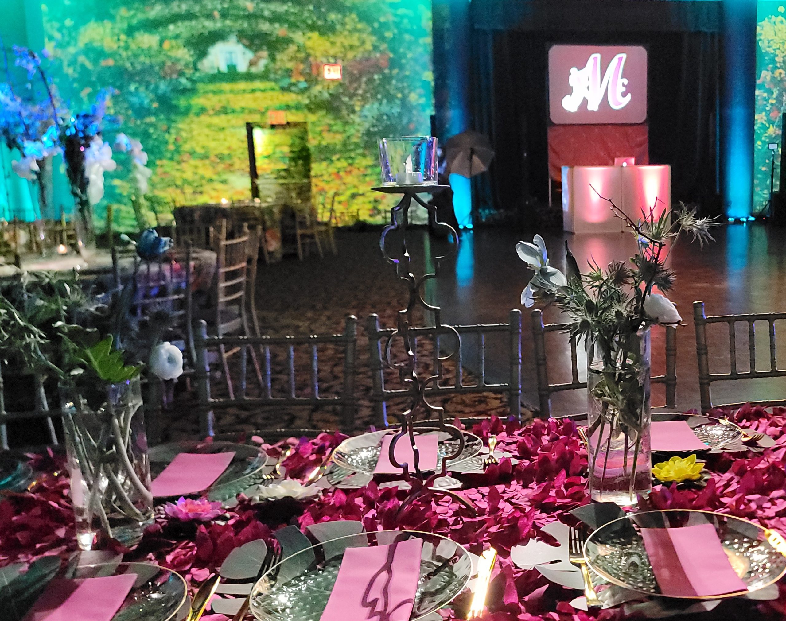 The Monet room: the garden painting on every wall, the petal-covered table in front, the monogram lit at the back