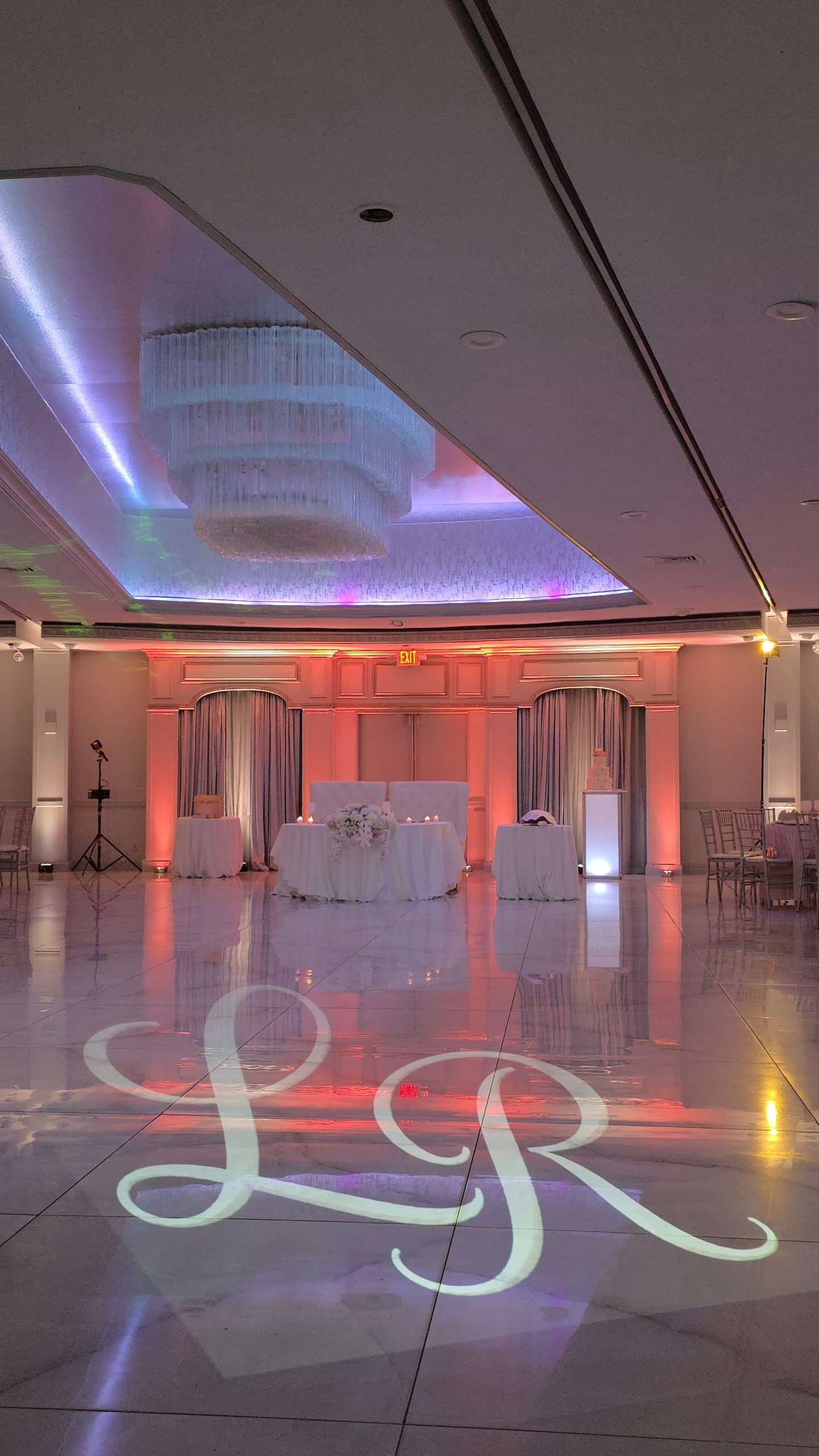 The lit ceiling panel and the sweetheart table, the room washed rose and blue
