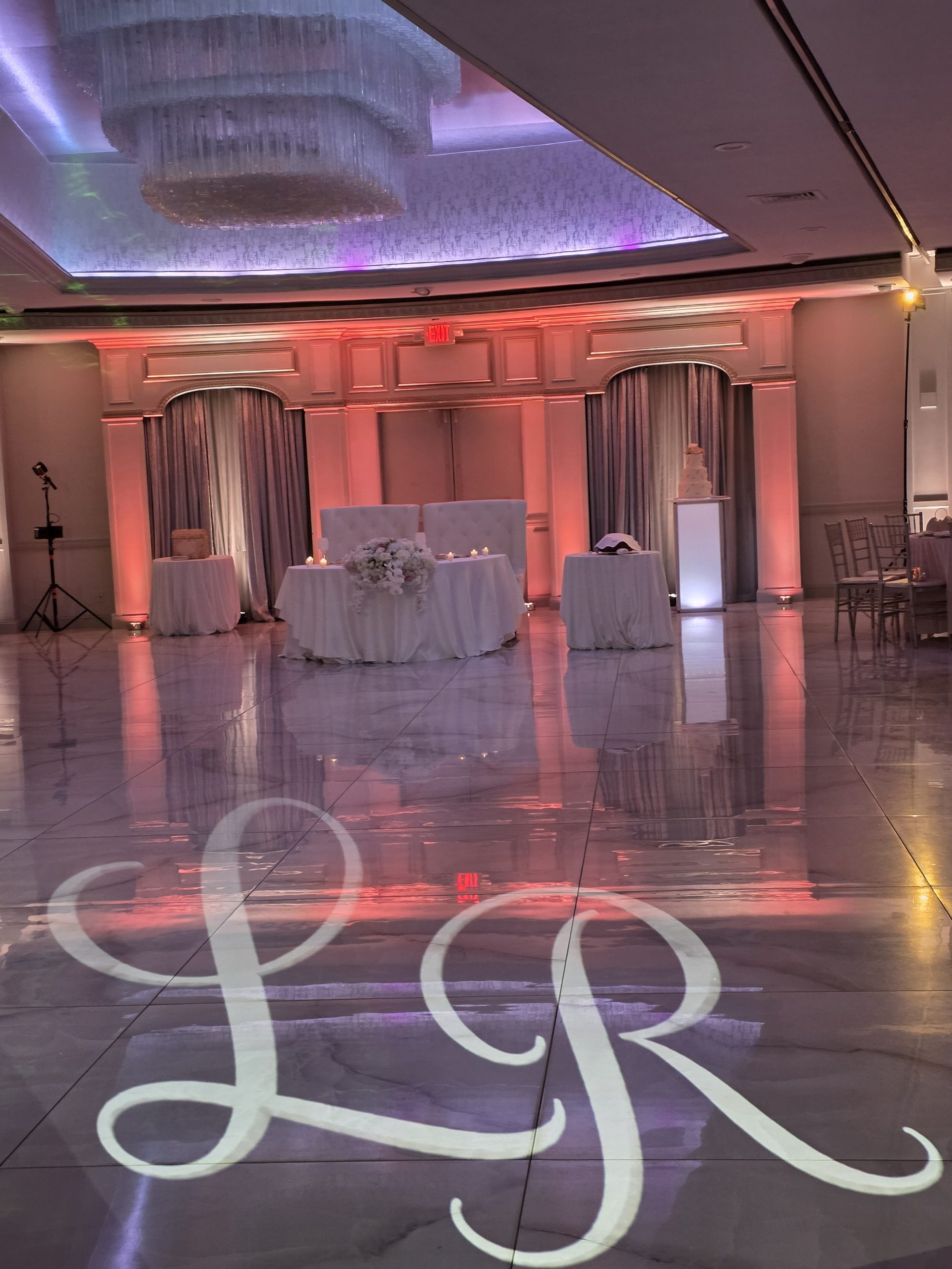 The projected initials on the dance floor and the rose-lit walls of the ballroom