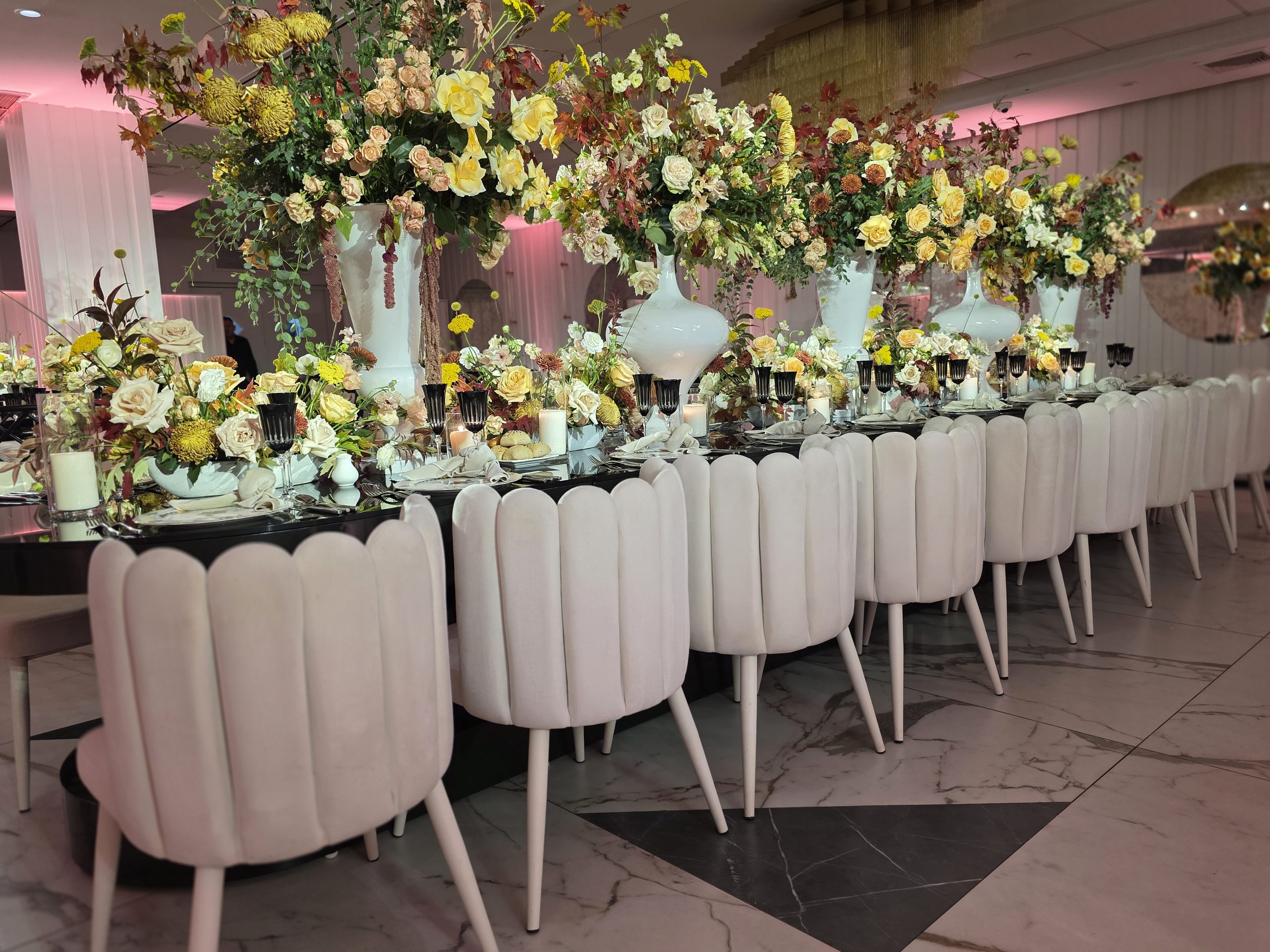 The long table of roses and white chairs down the room