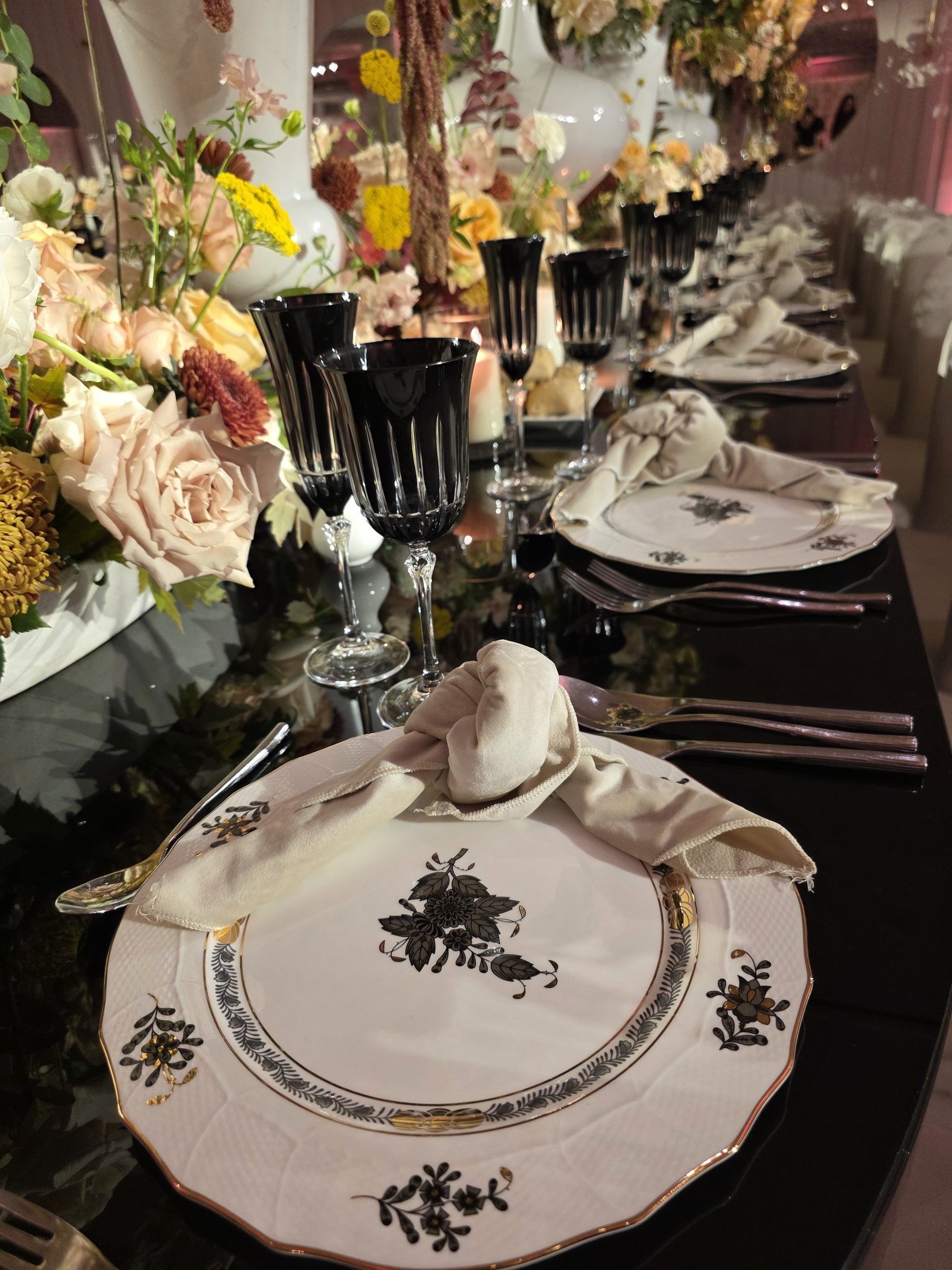 A place setting: black charger, the roses above, a candle