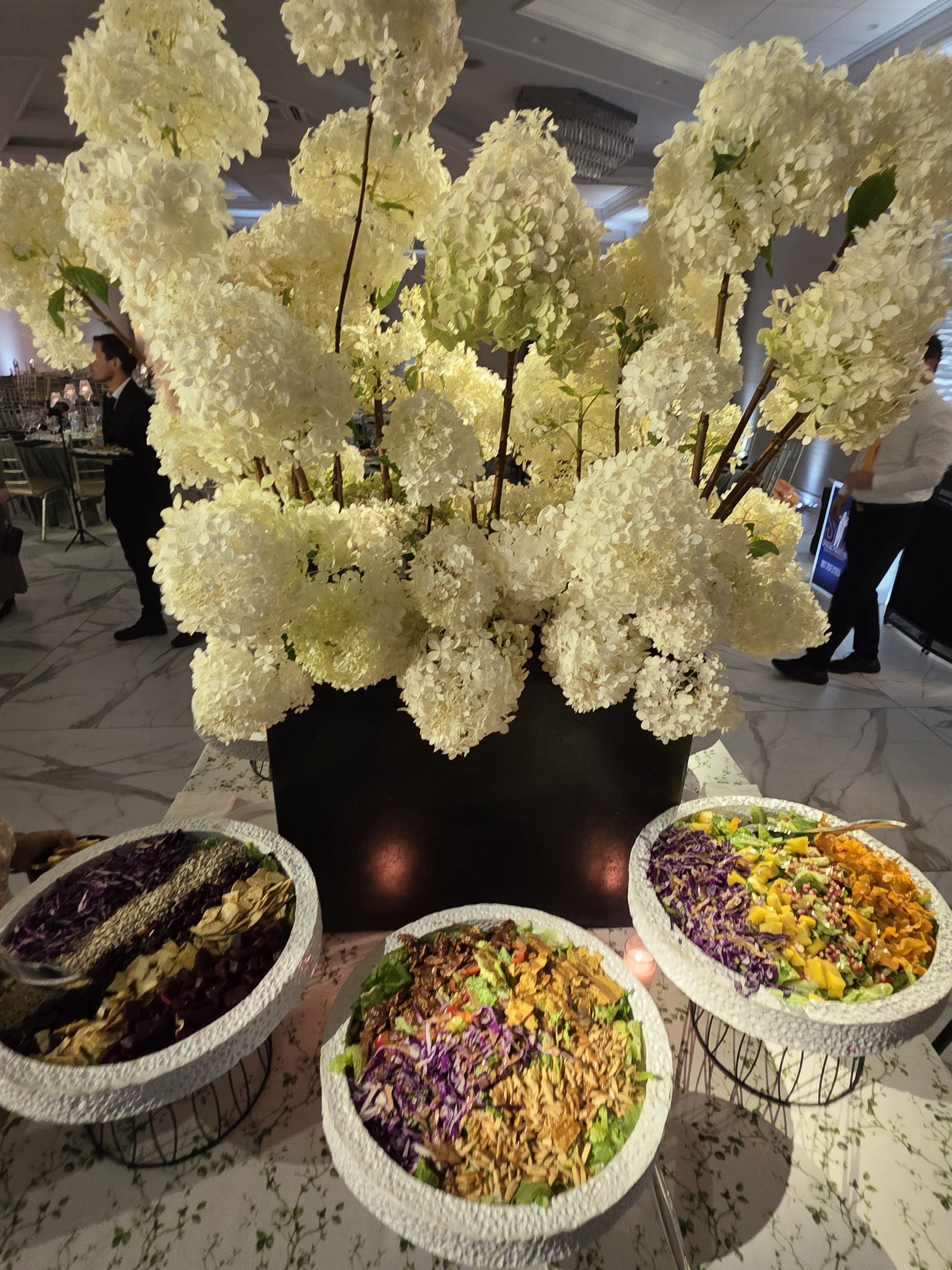 White hydrangea in a black urn over the salad bowls, marble floor