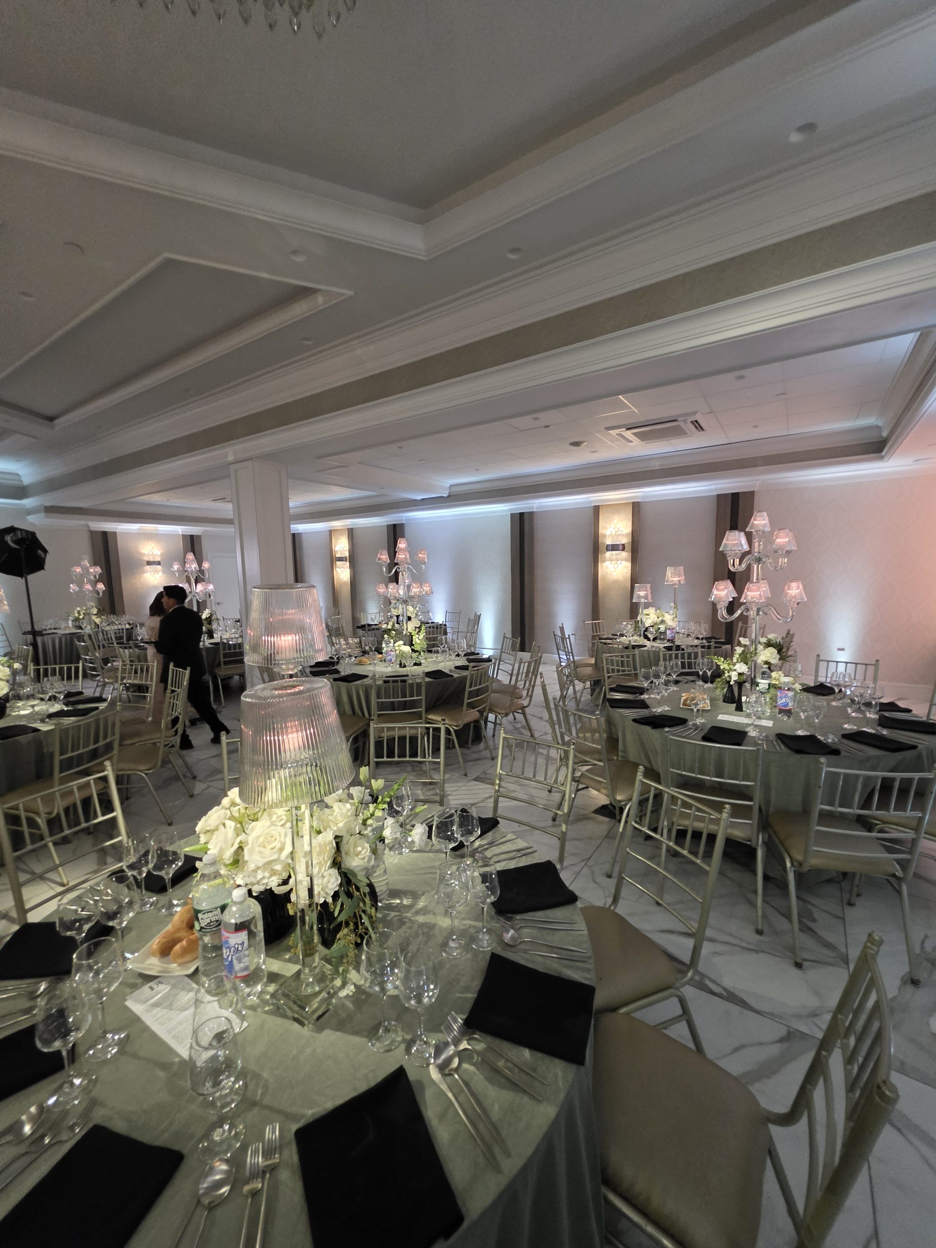 A round table set in sage and black, the candelabra lit, the room behind