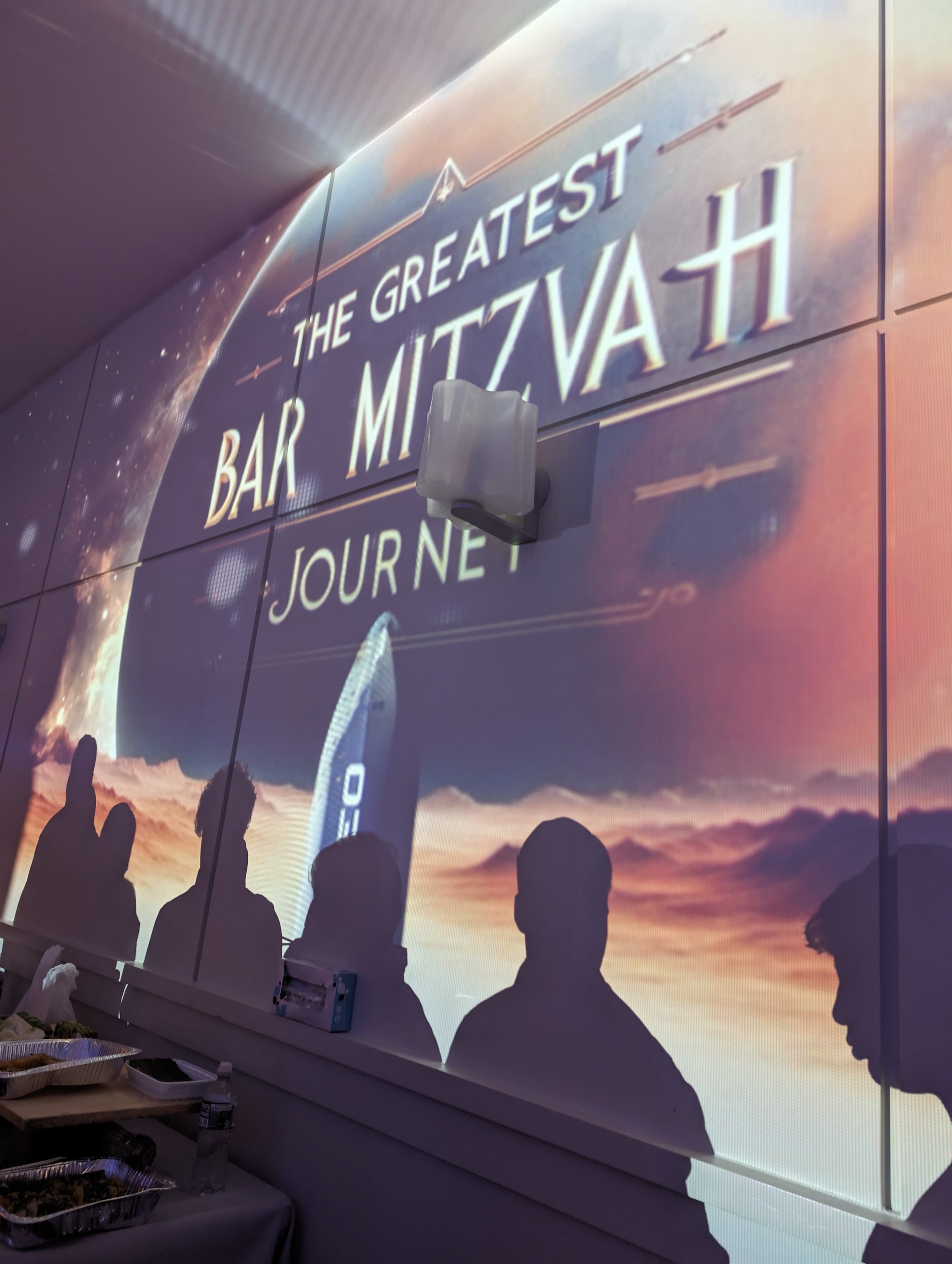 The Greatest Bar Mitzvah Journey, projected on the wall over the guests' silhouettes