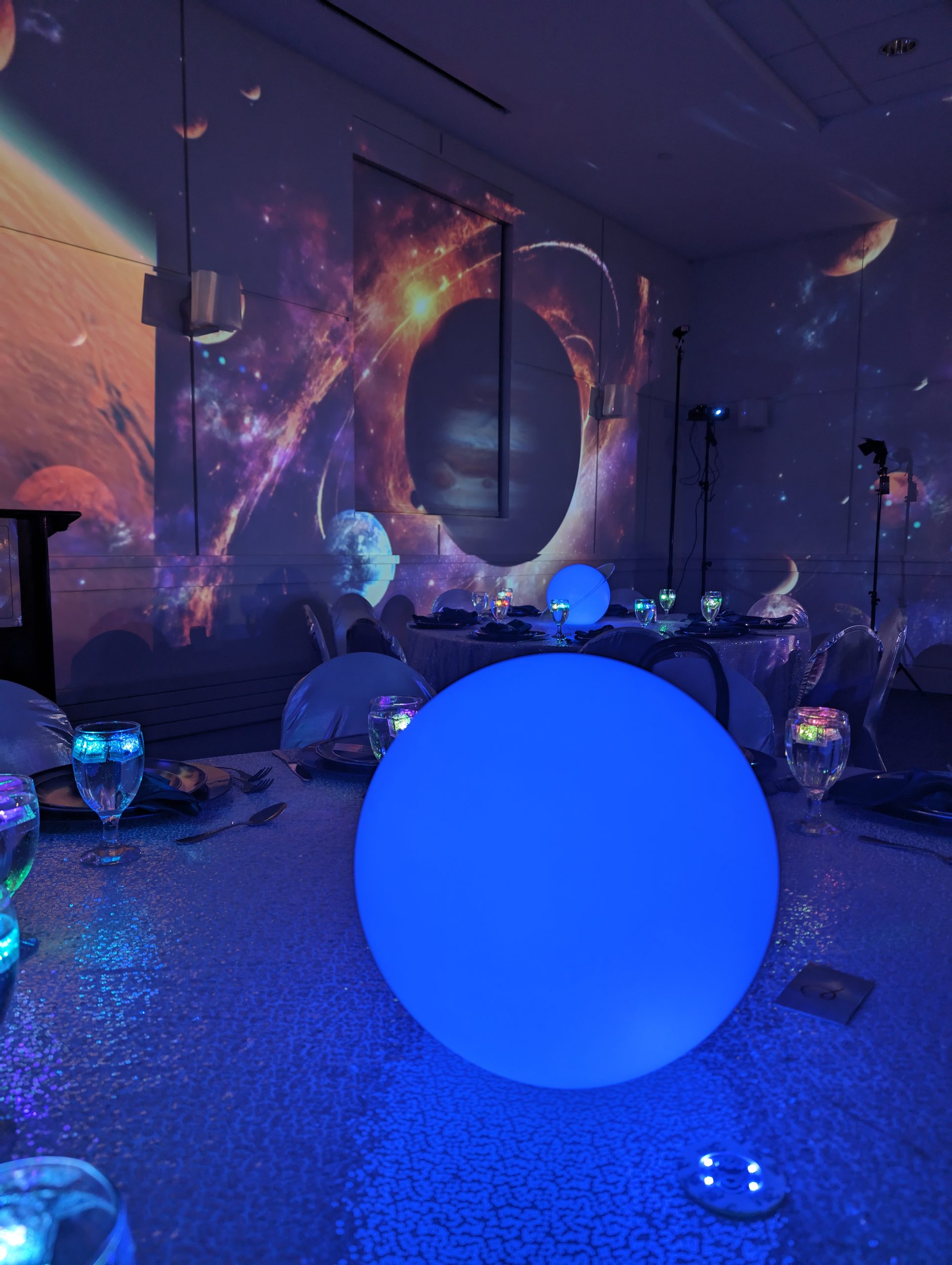 A ringed planet projected over the lounge, a glowing sphere on the table