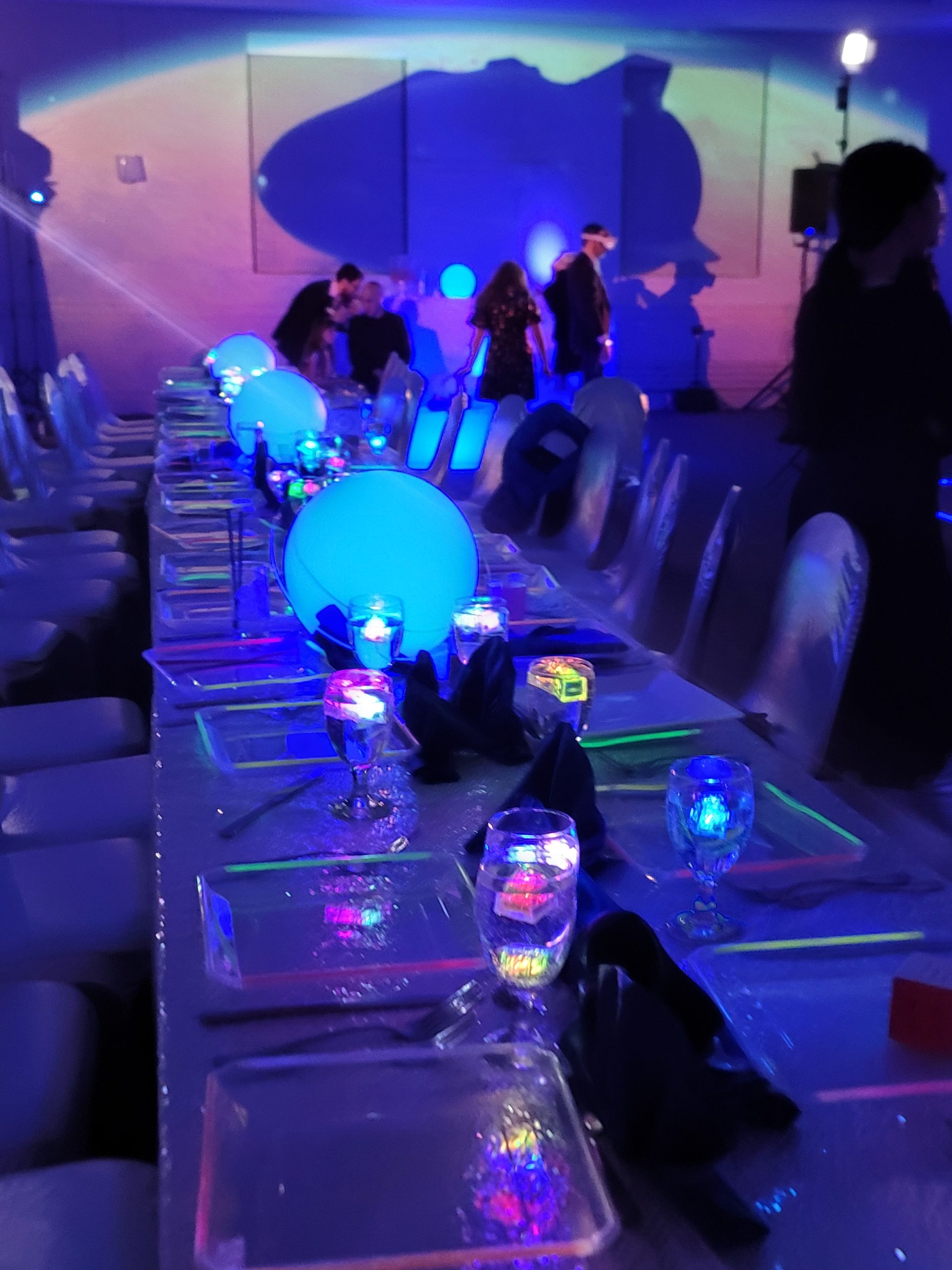 The spaceship's shadow across the far wall above a long table of glowing planets