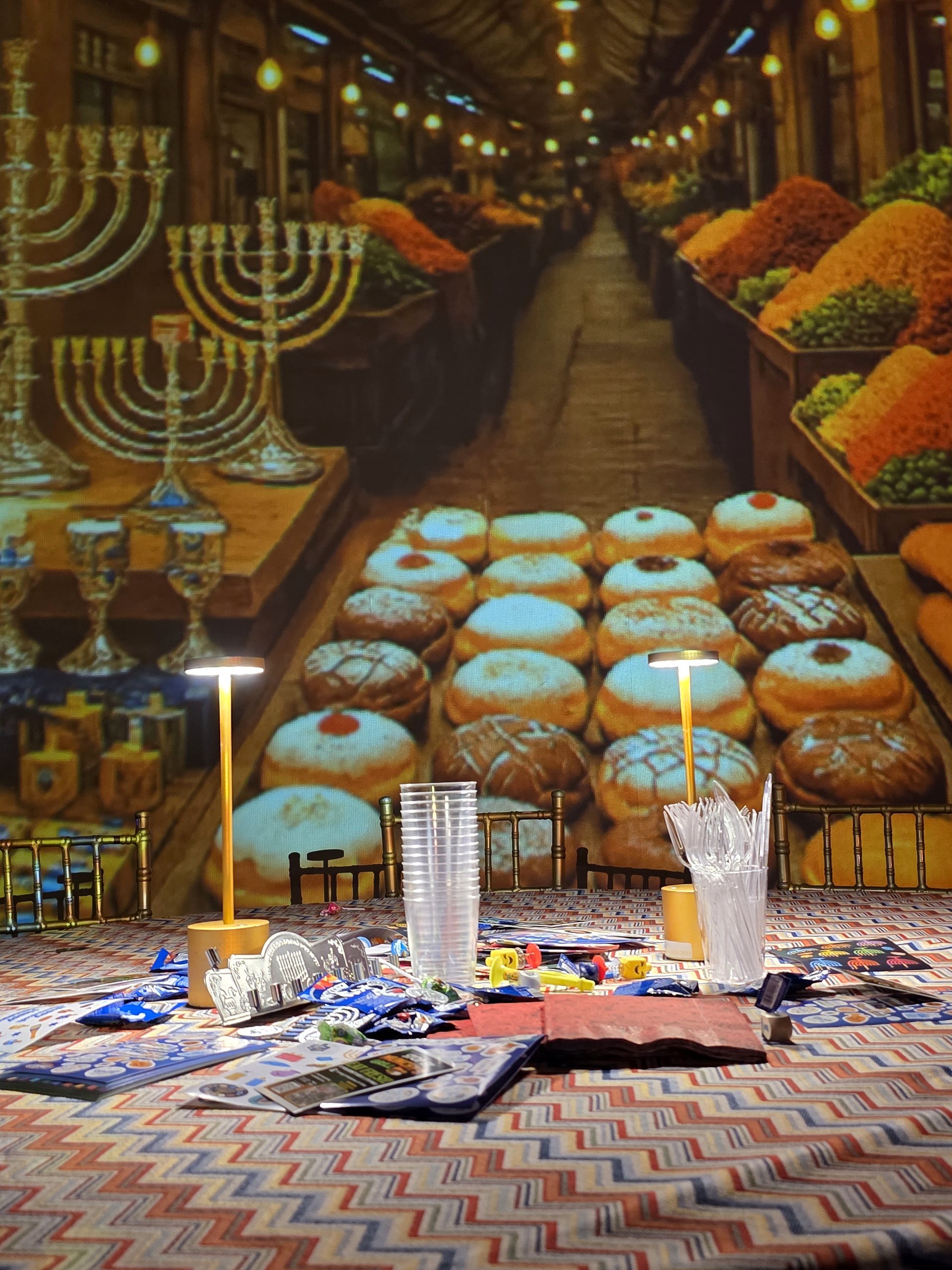 A projected market alley of sufganiyot and menorahs over the table