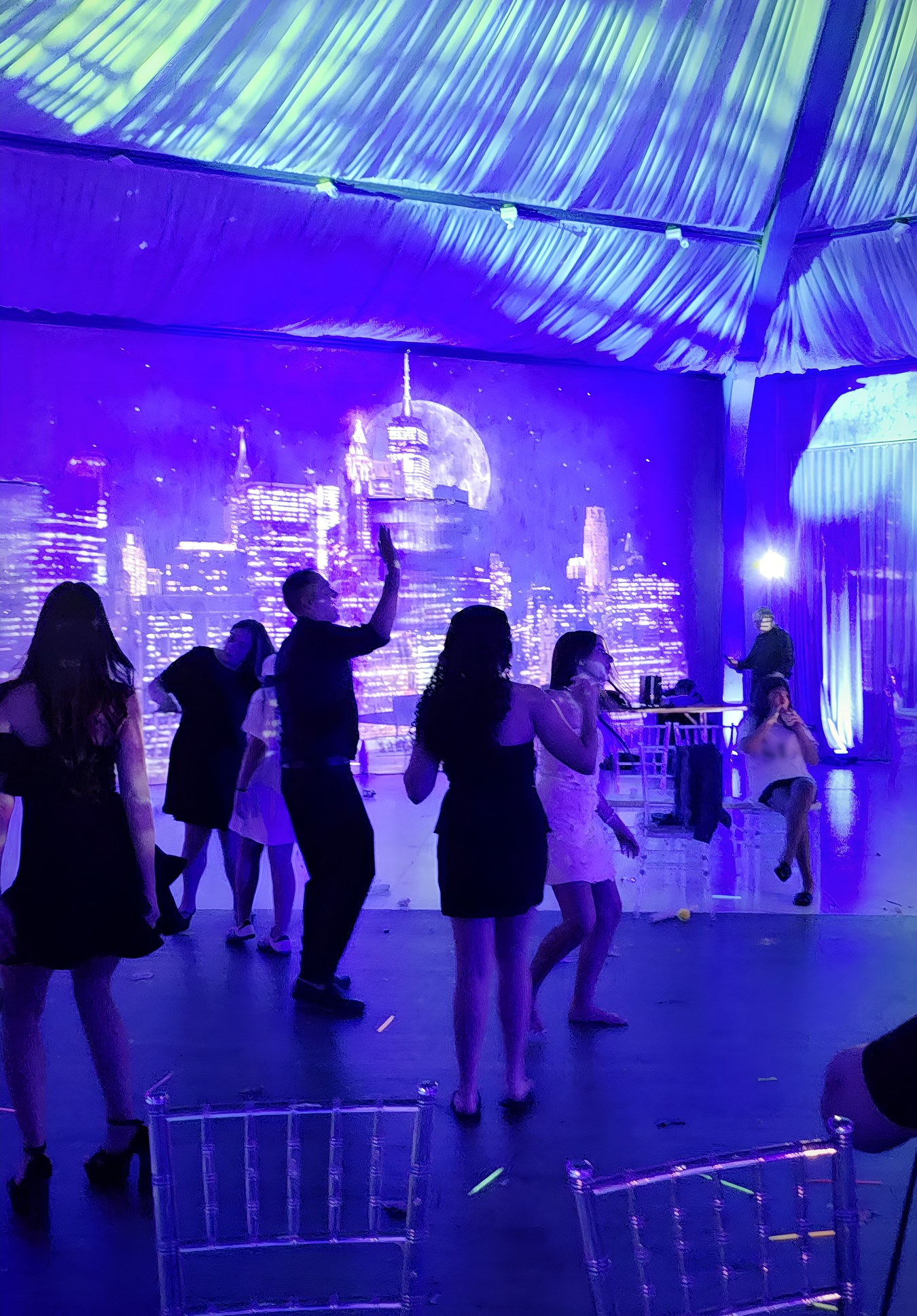 Later in the night: guests dancing in front of the skyline, the ceiling lit above