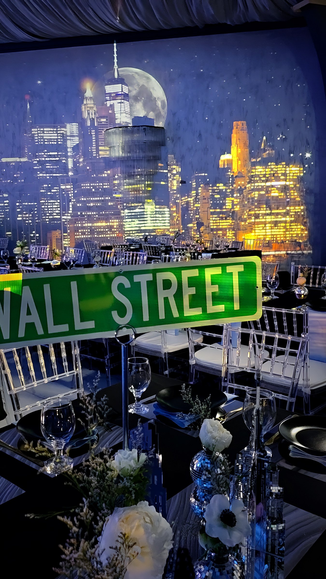 Before the guests came in: the skyline wall over the set tables, a crystal chandelier in front, a Wall Street sign on the table