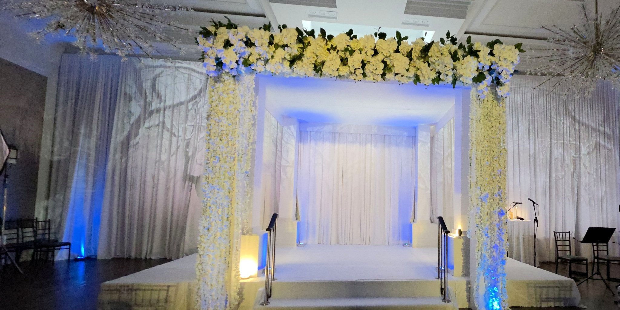The chuppah lit white, winter trees projected on the walls behind it