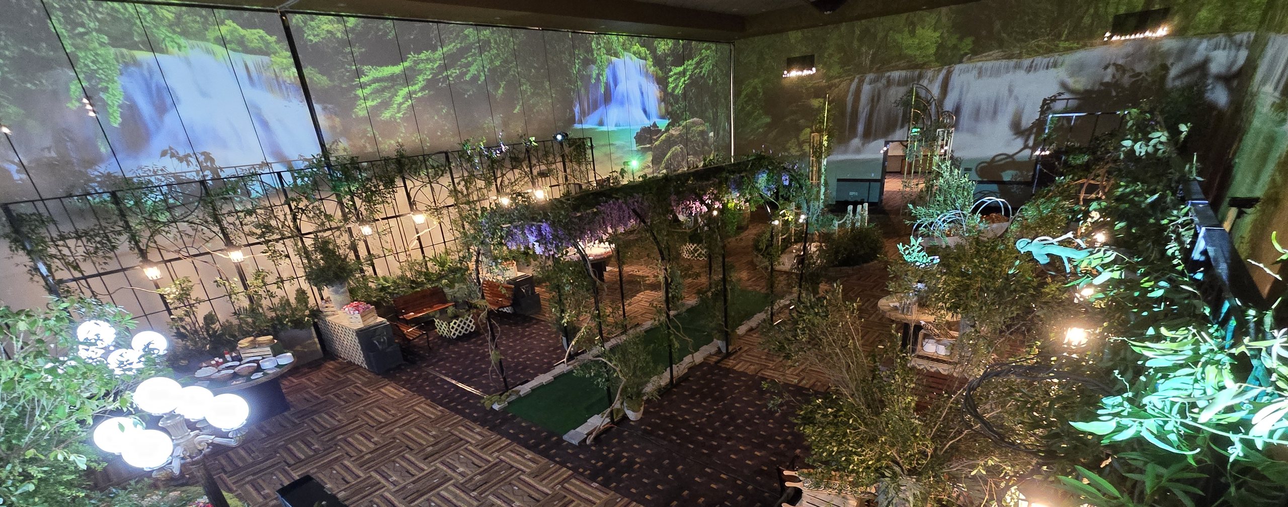 The whole room: trees, globes and garden arbours under the projected waterfall
