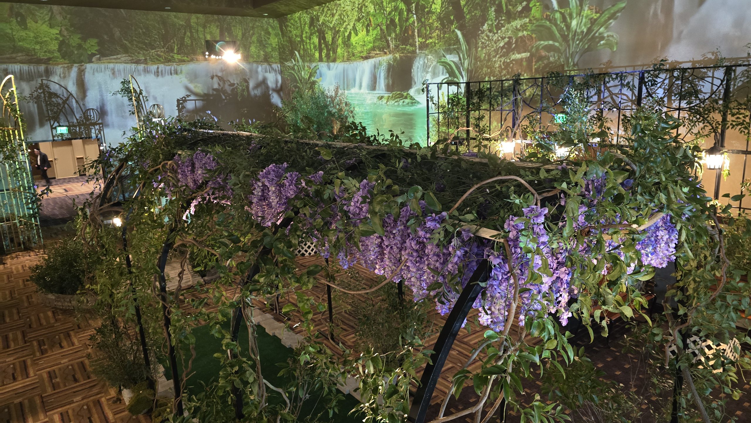 A wisteria arbour over the tables, the waterfall on the wall