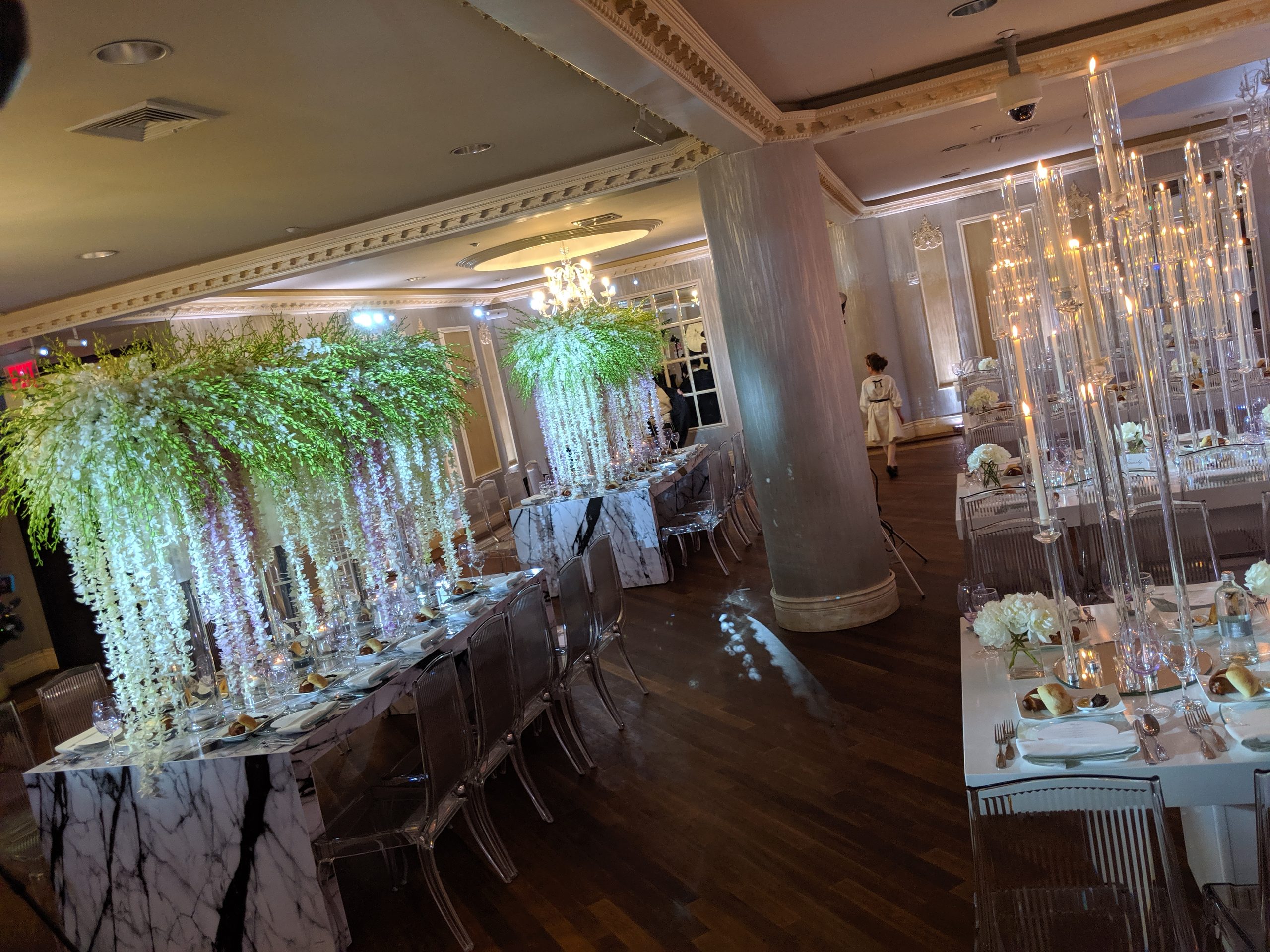 The whole room: wisteria, tapers, the marble tables, chandeliers above