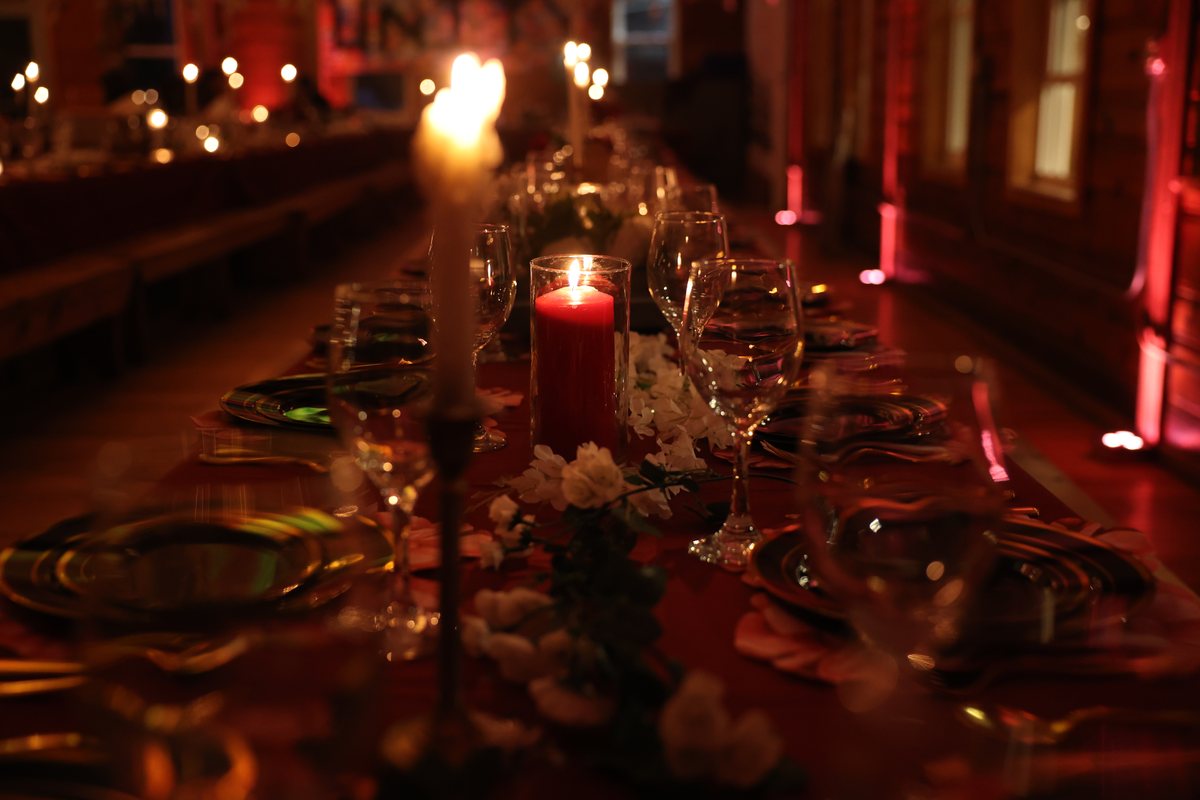 Candlelit long tables glowing red in a wooden hall
