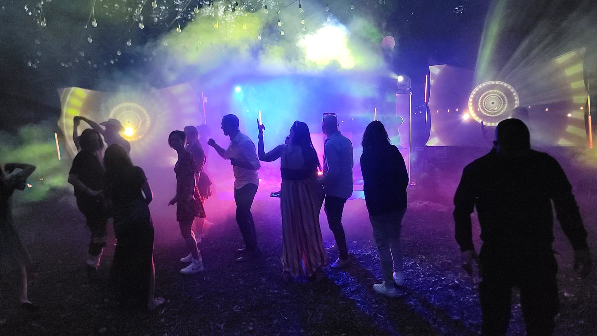 People dancing as silhouettes in haze and coloured light
