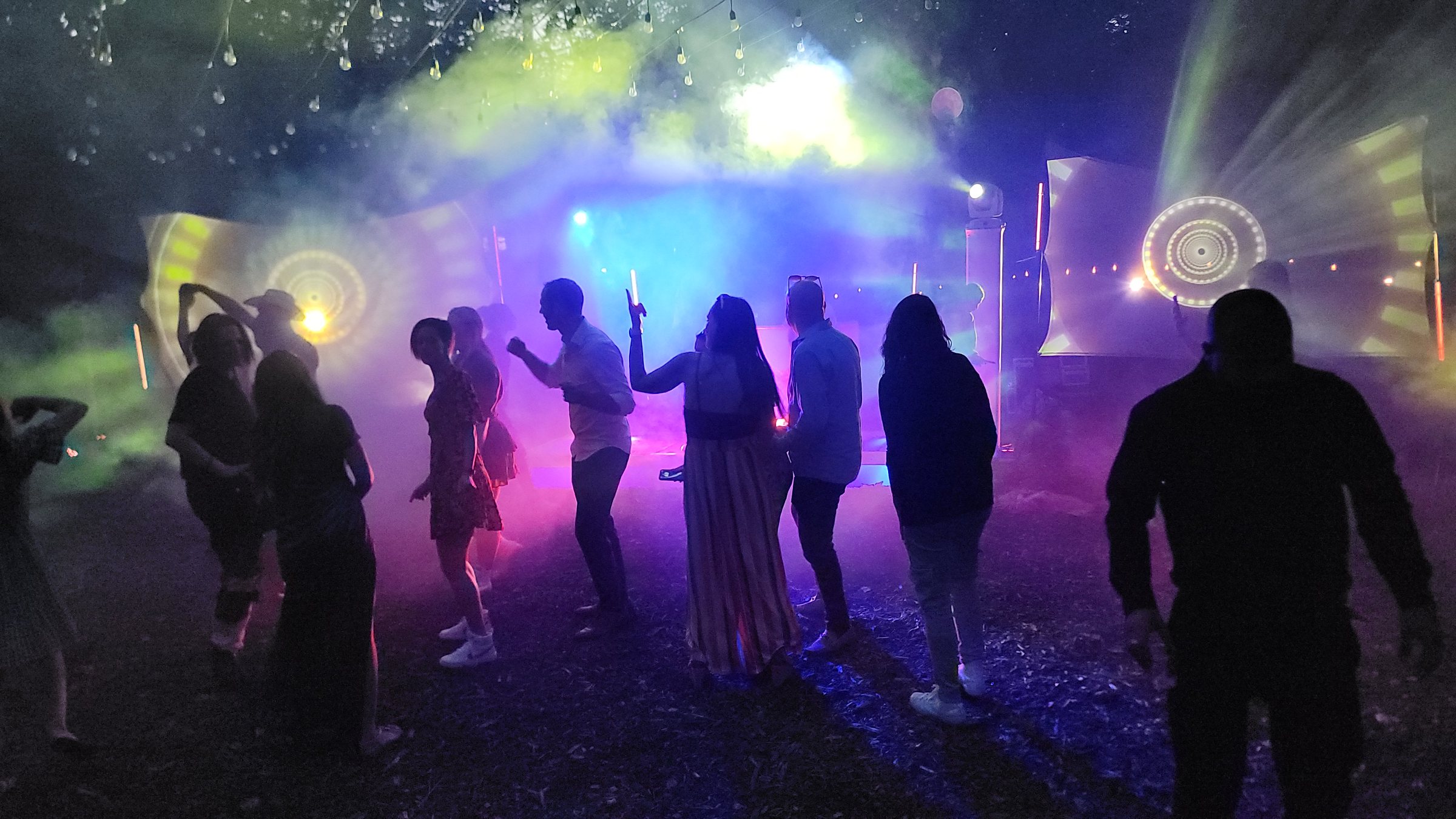 People dancing as silhouettes in haze and coloured light