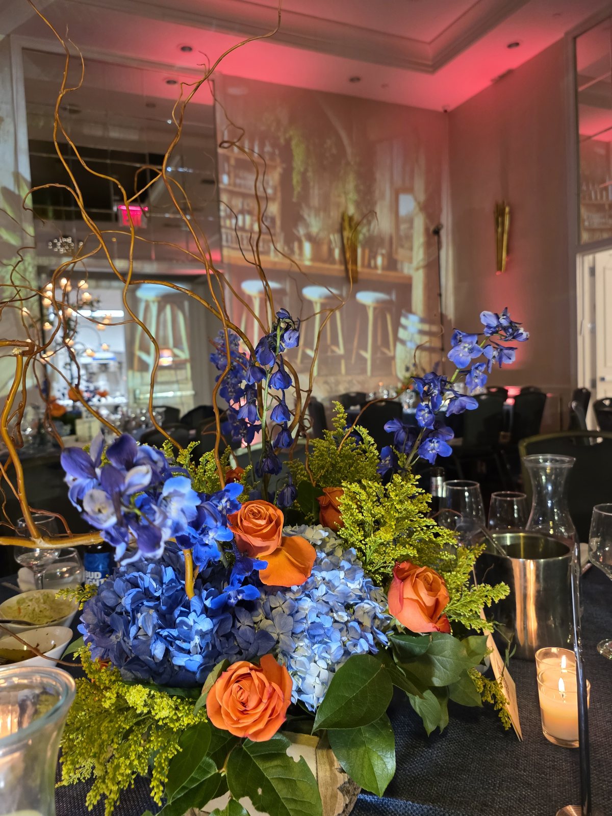 Blue hydrangea, delphinium and orange roses on the tables