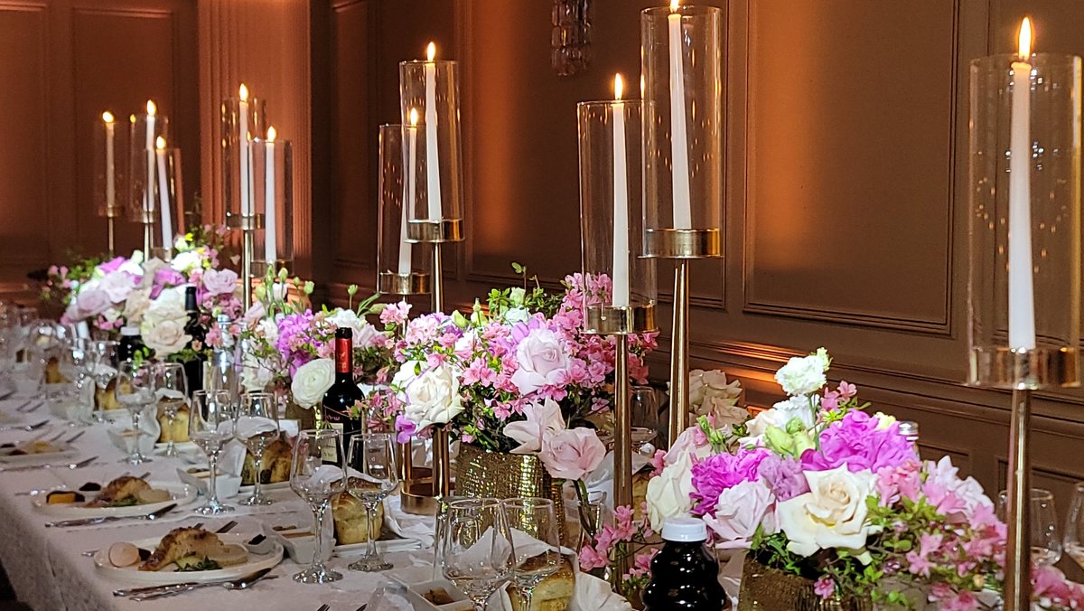 White florals and tapers in gold holders along the table