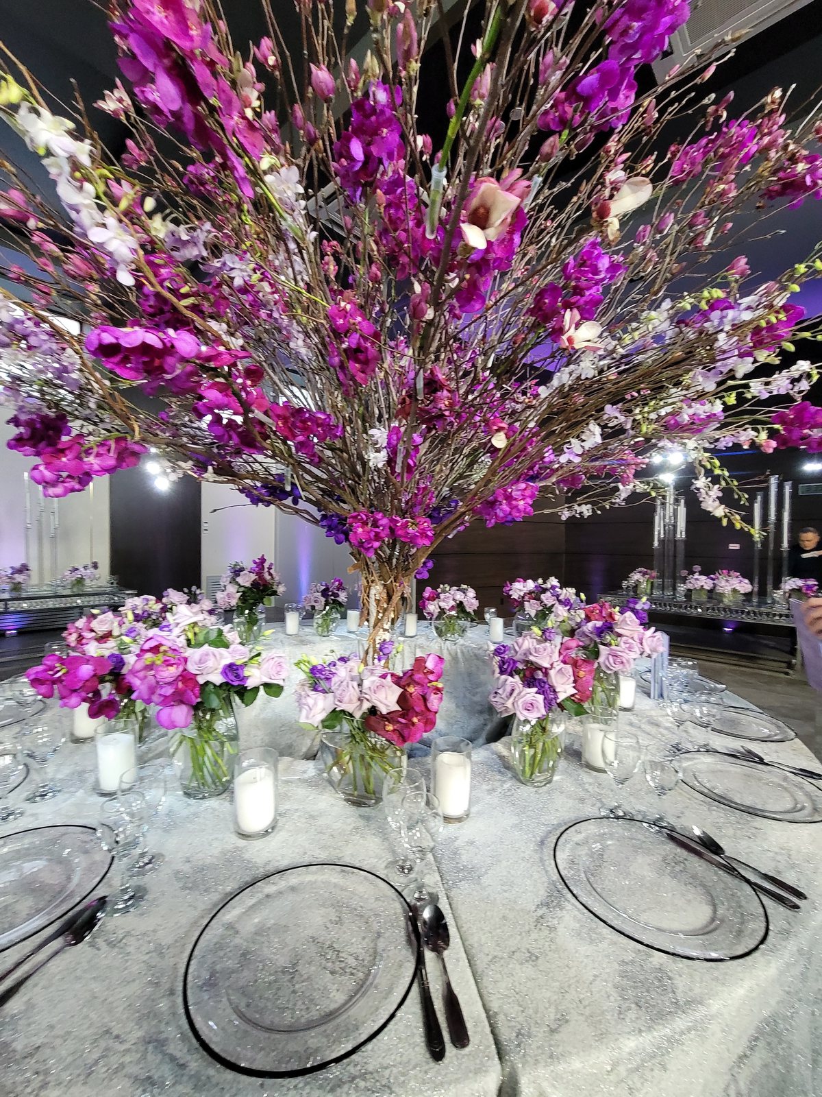 A tall orchid and delphinium centrepiece over the tables