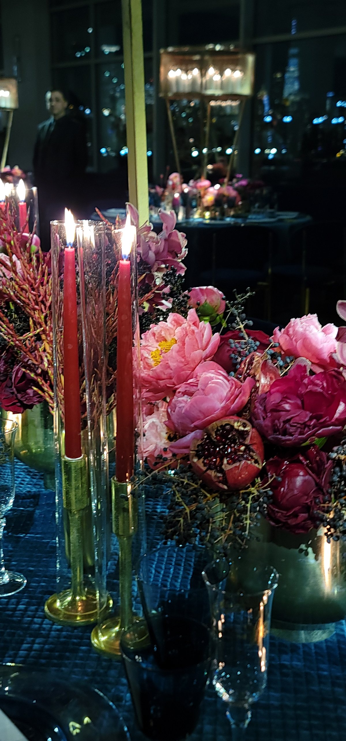 Peonies and coloured tapers on a dark table