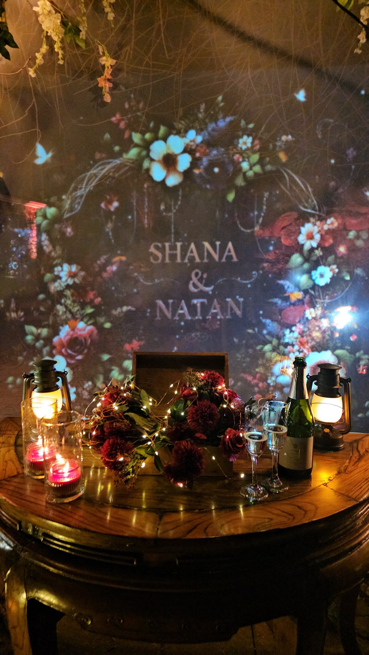The couple's names in projected flowers over lanterns