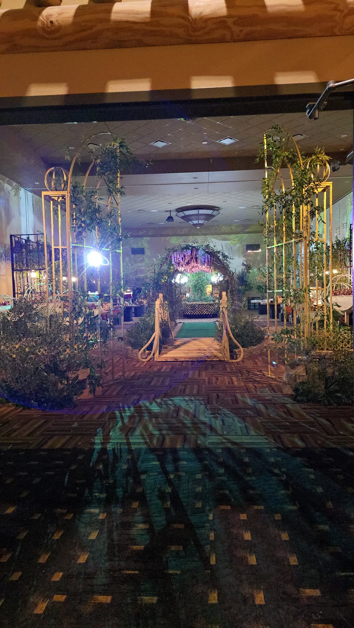 A garden bridge projected between real arches and greenery