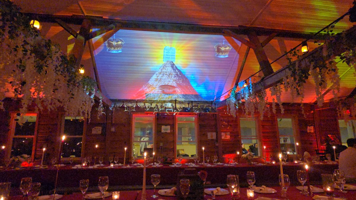 Colour projected across the peaked ceiling of a wooden hall over long tables