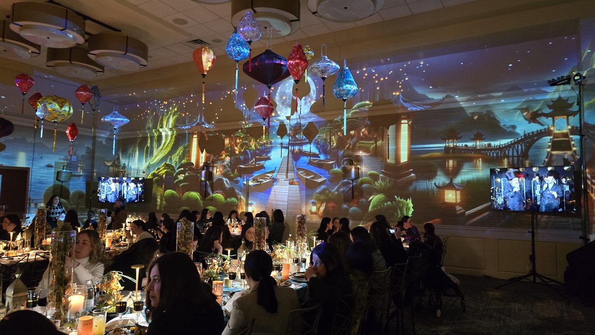 A sky and city projected around a full dinner under hanging lanterns